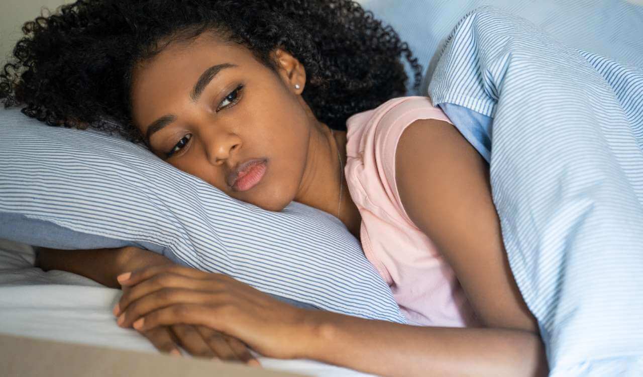 Eine Frau liegt auf einem Kissen und schläft. Wie hilft Akupressur dabei besser zu schlafen?